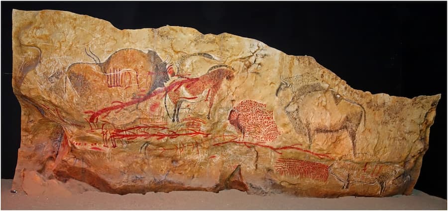 Various animals stand on the wall of a cave. It's possible, but far from certain, that they're standing on horizontal plants.