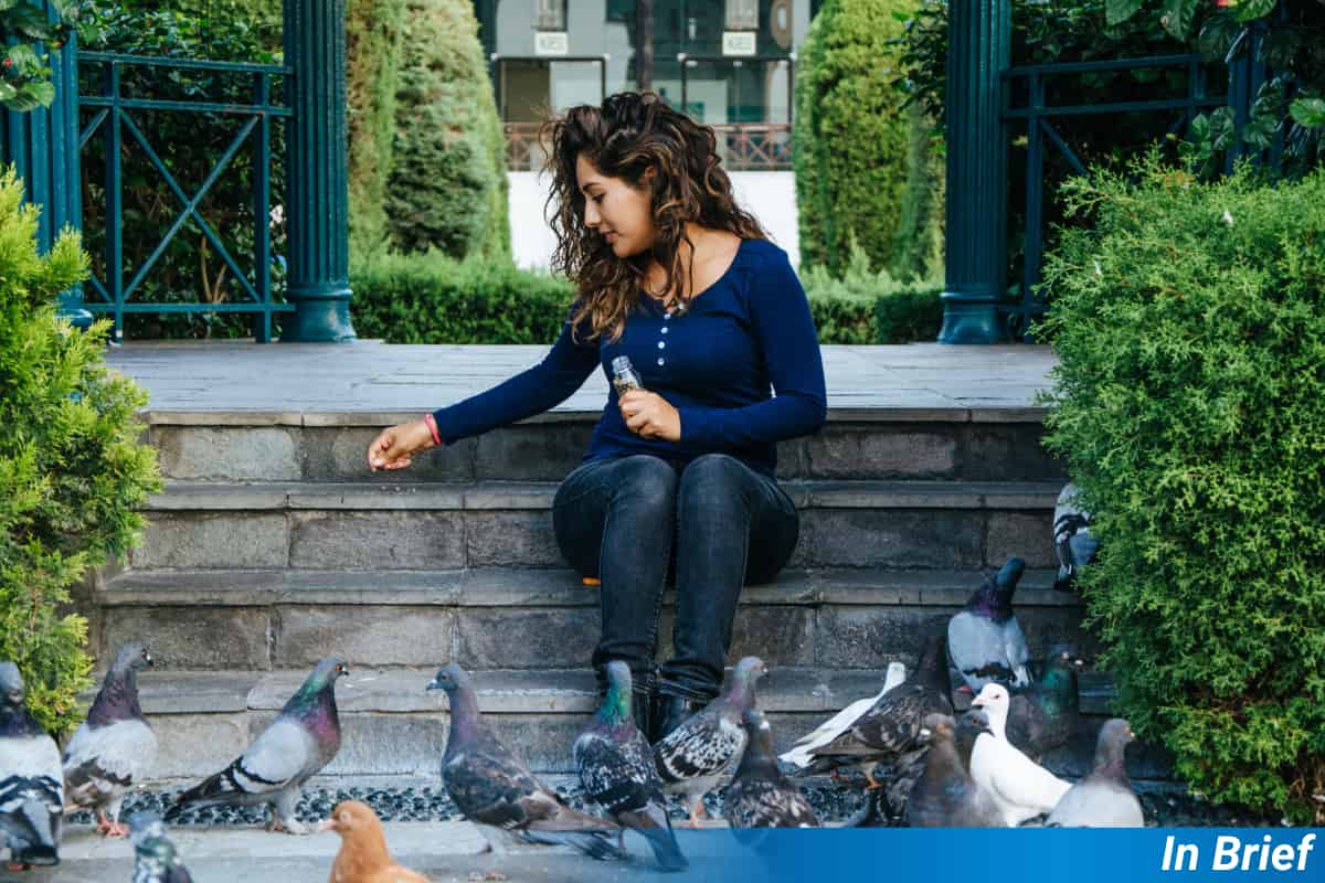A woman feeding the birds in a city