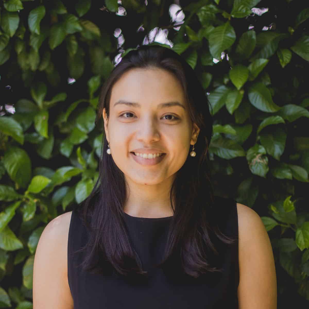 Dr. Juliane Ishida, a smiling woman with long dark hair wearing a black sleeveless top and pearl earrings, photographed again